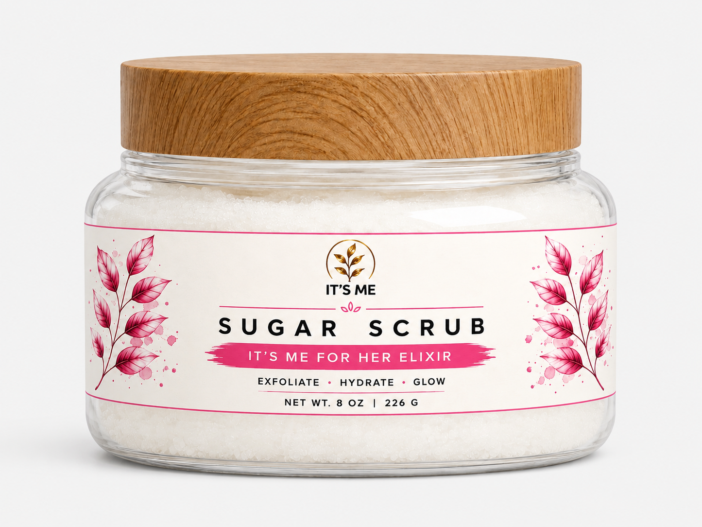 A jar of 'It's Me Sugar Scrub' with a light brown wooden lid and a white label featuring pink floral illustrations, set against a plain white background.