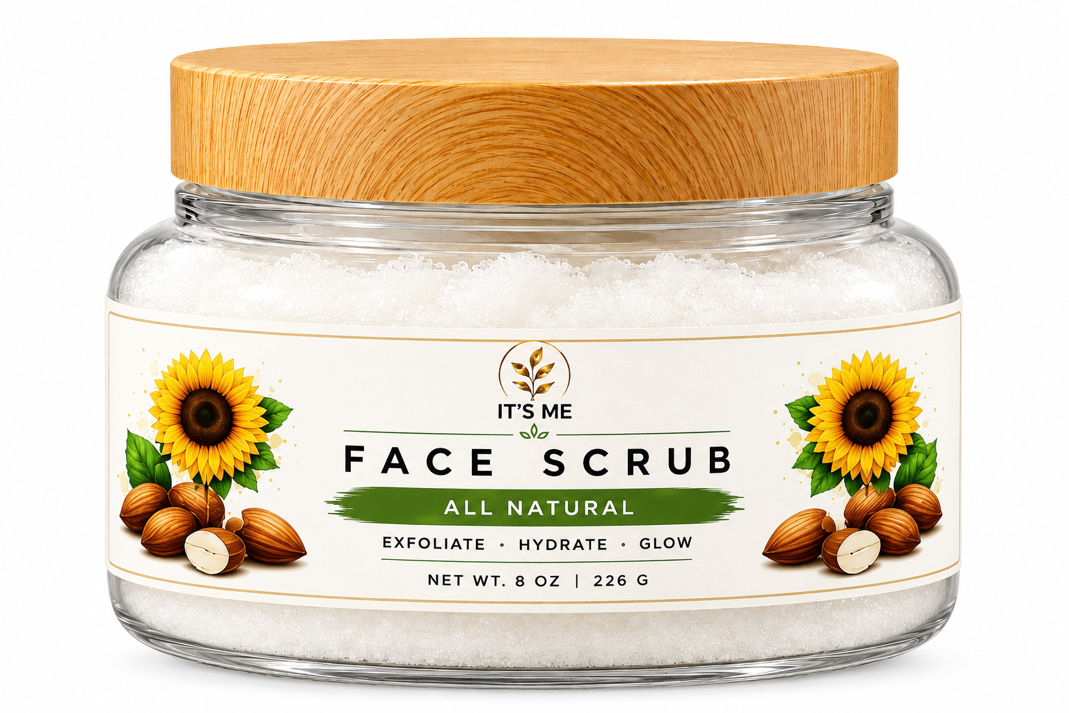 A clear glass jar of It's Me Face Scrub with a light wood lid, containing white exfoliating scrub. The front label features illustrations of sunflowers, almonds, and olives, with text reading 'FACE SCRUB ALL NATURAL'.