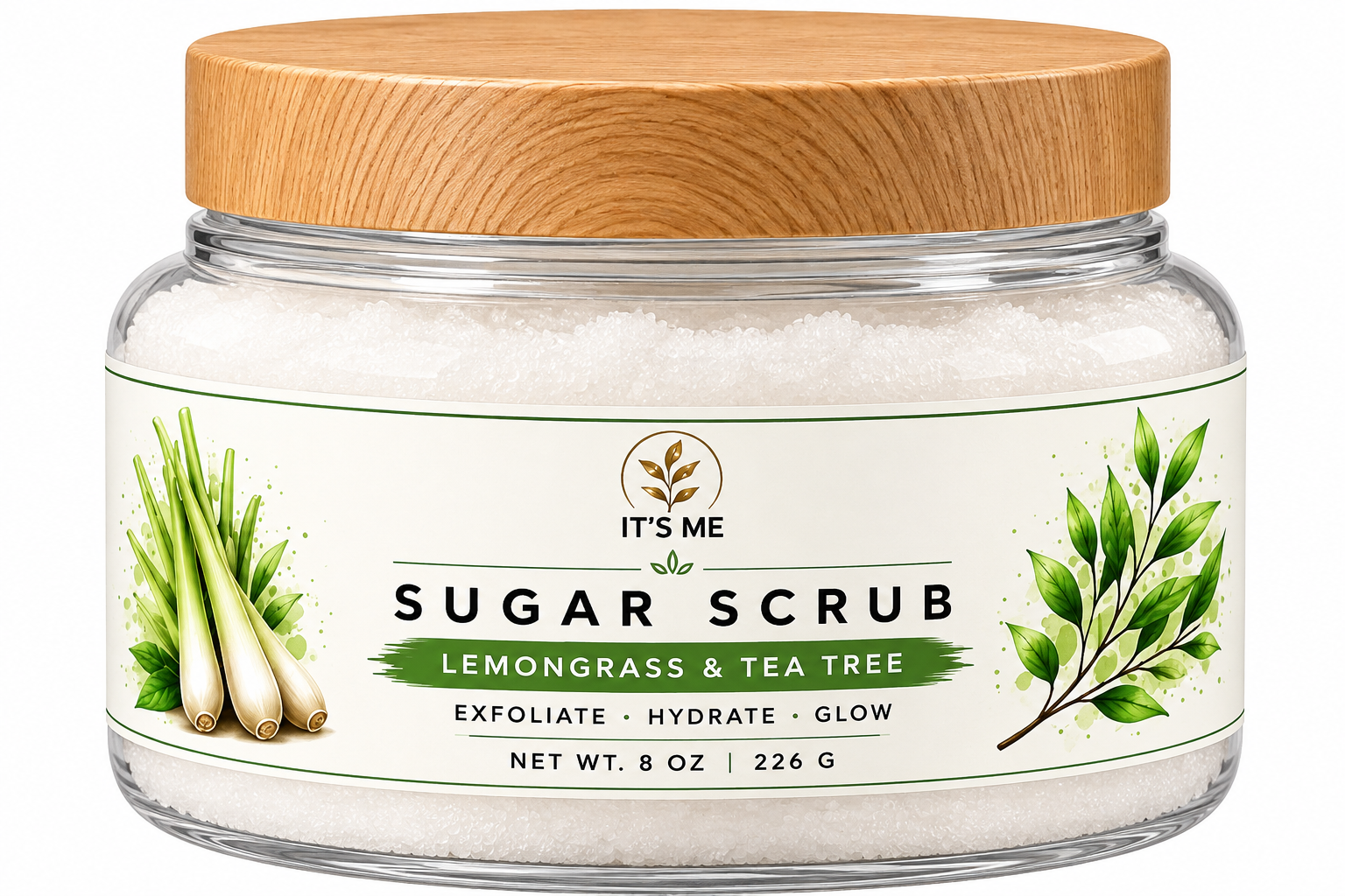 A clear glass jar of It's Me Sugar Scrub with a light wood lid, containing white exfoliating sugar crystals. The label features green and white graphics with illustrations of lemongrass and a tea tree branch, and text reading 'SUGAR SCRUB' and 'LEMONGRASS & TEA TREE'.